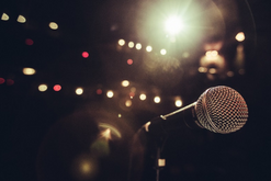 Microphone on stage with a spotlight and lights in the background