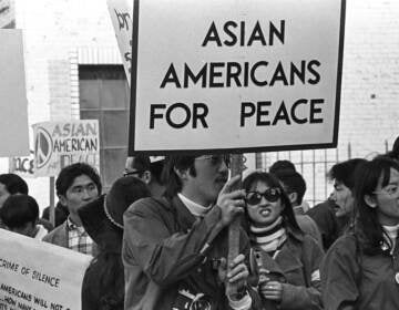 Asian Americans protesting and holding a sign that says 