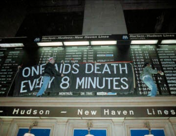 Members of the group Act-Up hang a banner across the train schedule board in New York's Grand Central Terminal