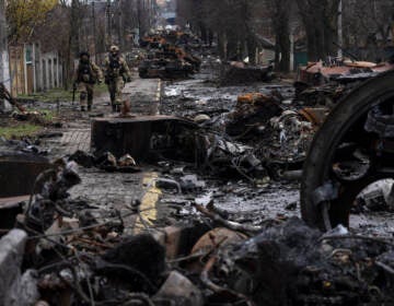 Soldiers walk amid destroyed Russian tanks in Bucha, in the outskirts of Kyiv, Ukraine, Sunday, April 3, 2022. Ukrainian troops are finding brutalized bodies and widespread destruction in the suburbs of Kyiv, sparking new calls for a war crimes investigation and sanctions against Russia.