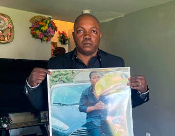 Peter Lyoya holds up a picture of his son Patrick Lyoya, 26, in his home in Lansing, Mich., on April 14. Patrick was facedown on the ground when he was fatally shot in the head by a Grand Rapids police officer this month.