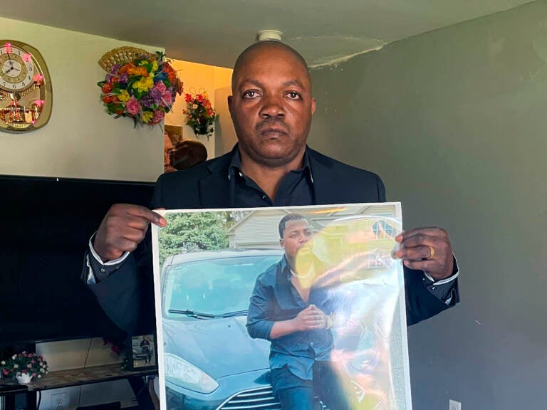 Peter Lyoya holds up a picture of his son Patrick Lyoya, 26, in his home in Lansing, Mich., on April 14. Patrick was facedown on the ground when he was fatally shot in the head by a Grand Rapids police officer this month.