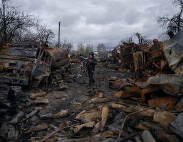 A man walks with a bicycle in a street with destroyed Russian military vehicles near Chernihiv