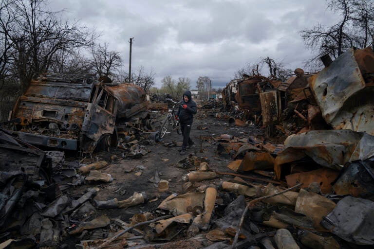A man walks with a bicycle in a street with destroyed Russian military vehicles near Chernihiv