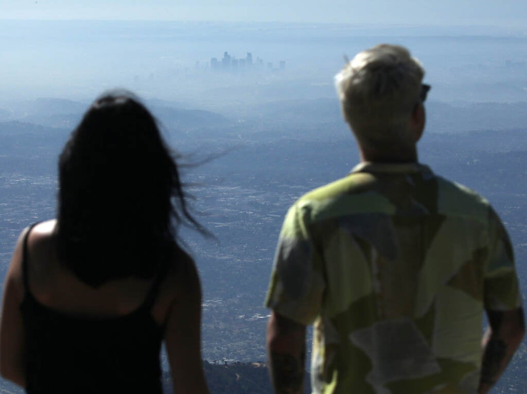 People take in the view with the buildings of downtown Los Angeles partially obscured