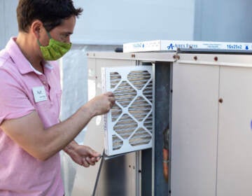 Mark Marston slides a MERV 13 air filtration filter back into the HVAC system outside of a gym