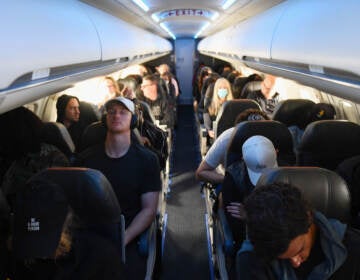 Airplane passengers, some not wearing face masks