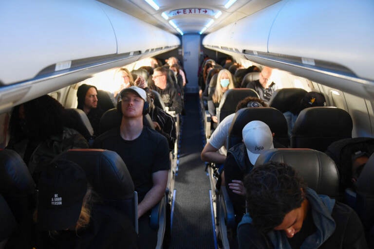 Airplane passengers, some not wearing face masks