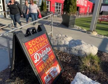 A sign outside the Lansing Brewing Company in Lansing, Michigan advertises a social district where people can buy alcohol-to-go and drink it within the boundaries of an outdoor downtown zone. (Sarah Lehr)