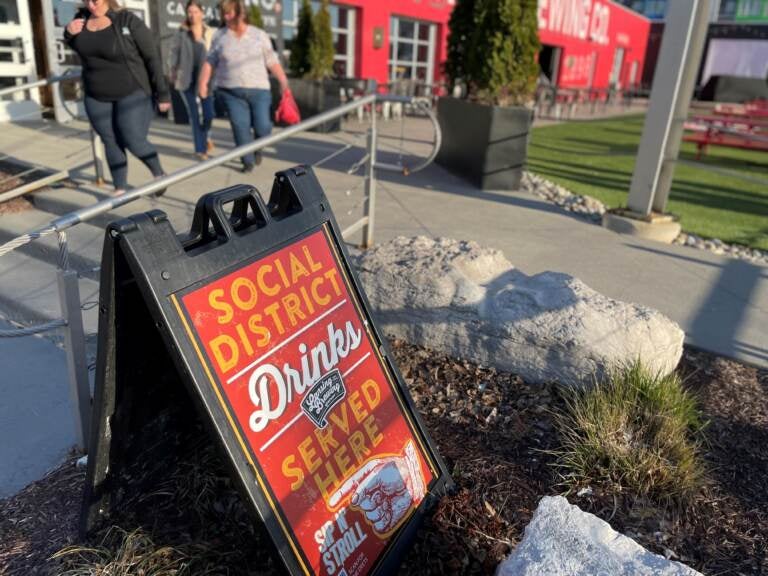A sign outside the Lansing Brewing Company in Lansing, Michigan advertises a social district where people can buy alcohol-to-go and drink it within the boundaries of an outdoor downtown zone. (Sarah Lehr)
