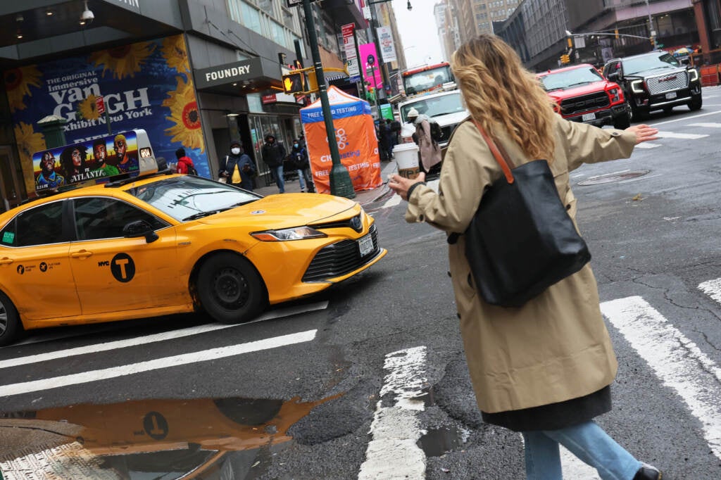 A woman attempts to haul down a yellow cab