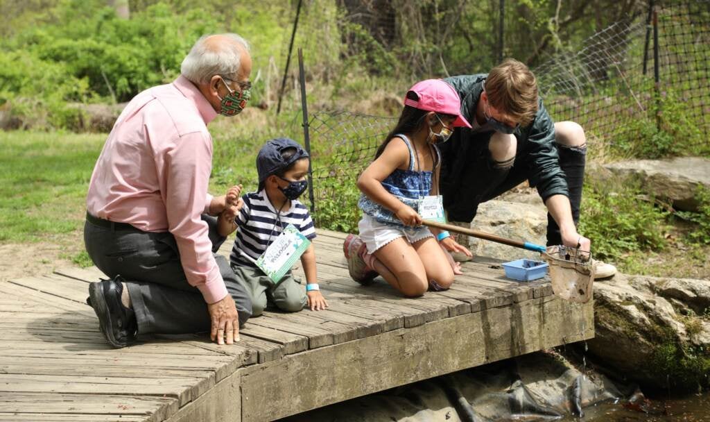 Two adults sit with two children on a Schuylkill River dock