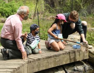 Two adults sit with two children on a Schuylkill River dock