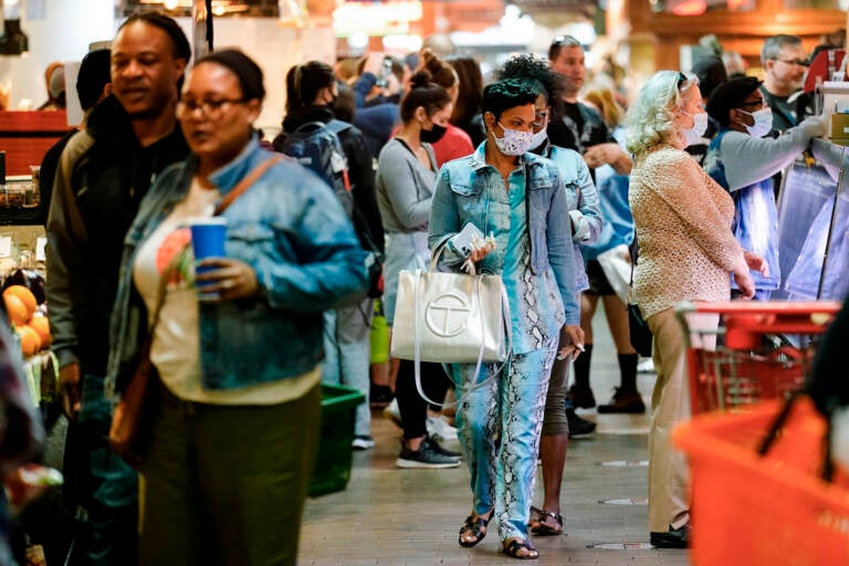 Customers, some wearing face masks, patronize the Reading Terminal Market