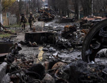 Soldiers walk amid destroyed Russian tanks in Bucha