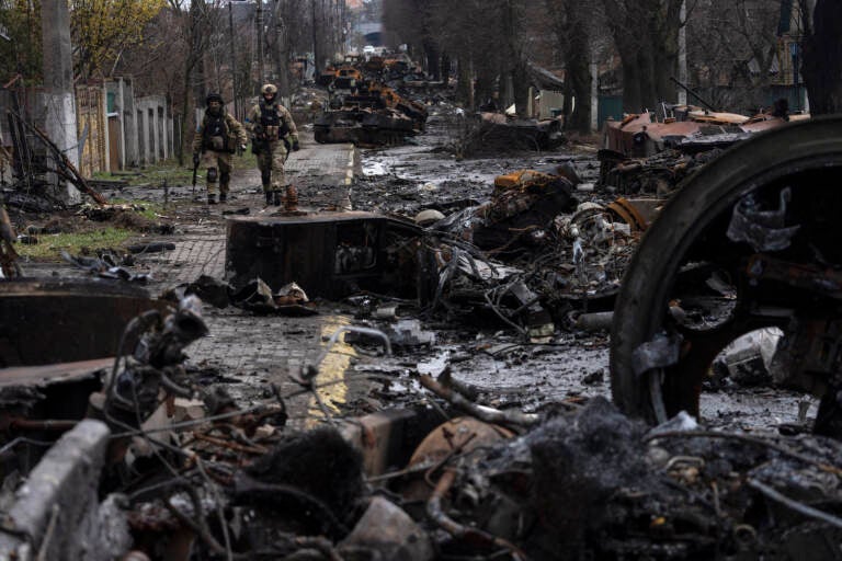 Soldiers walk amid destroyed Russian tanks in Bucha