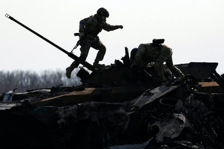 A Ukrainian serviceman walks on a destroyed Russian fighting vehicle in Bucha