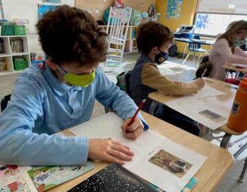 Students wearing face masks write letters at their desks