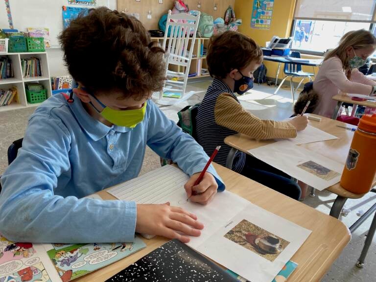 Students wearing face masks write letters at their desks