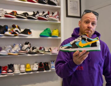 Suplex co-owner Mike Molino holds a Chunky Dunks, Ben and Jerry’s, Nike collaboration sneaker at Suplex’s sneaker store in Philadelphia. (Kimberly Paynter/WHYY)