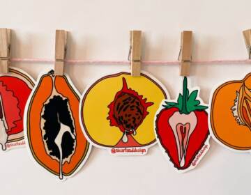 Art featuring fruit hangs on a white wall.