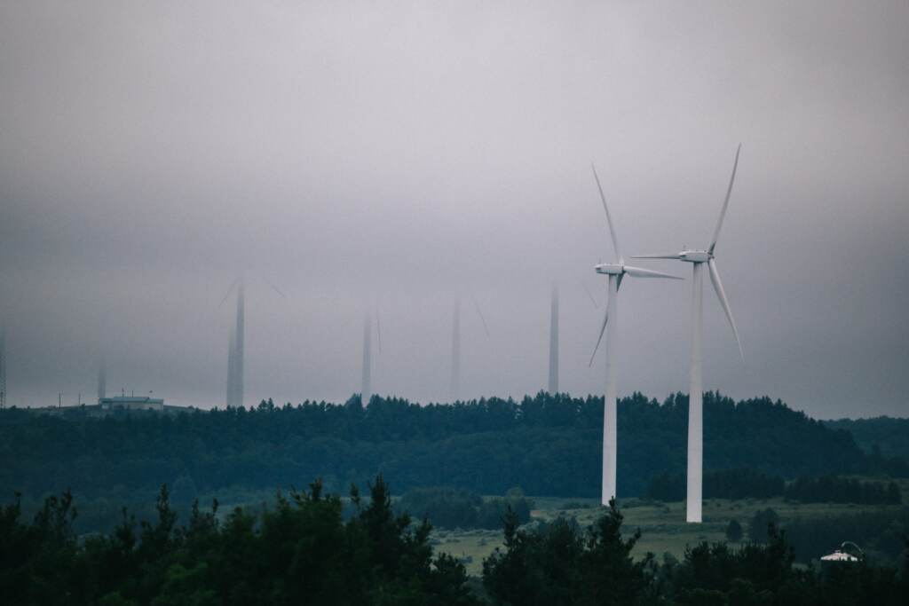 A wind energy farm is visible with cloudy skies in the background.