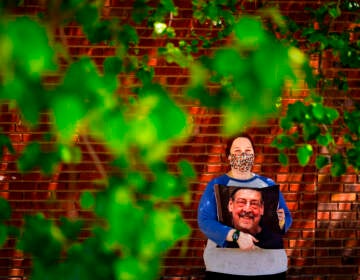 Sara Atkins poses for a photo, in Wynnewood, Pa., Tuesday, May 10, 2022, while holding a pillow with an image of her father Andy Rotman-Zaid, who died of COVID-19 in December 2020. She channels her grief into fighting for global vaccination and better access to health care to honor her father.