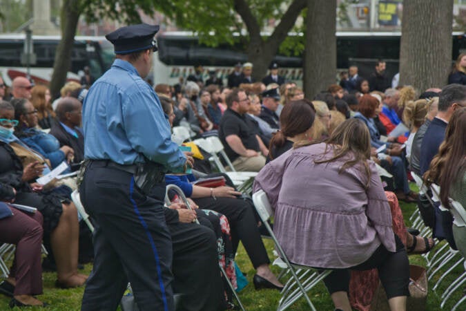 A Philadelphia police officer offered tissues to grieving family members at the Living Flame Memorial Service on May 4, 2022. (Kimberly Paynter/WHYY)