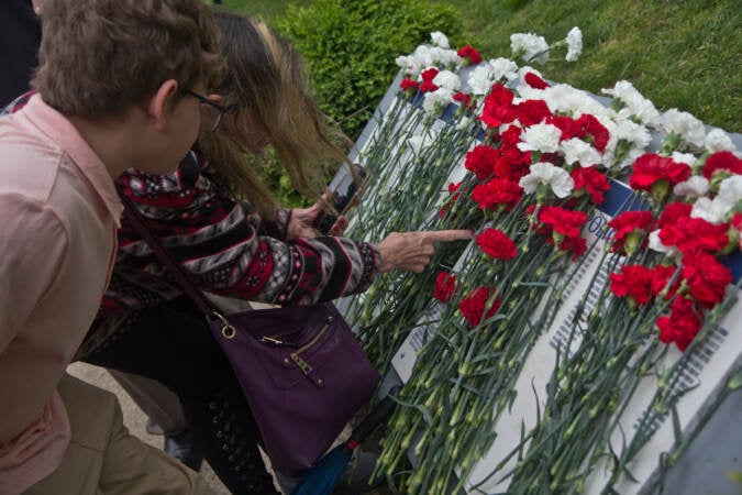 Family members found the names of their loved ones at the Living Flame Memorial in Philadelphia’s Franklin Square Park on May 4, 2022. (Kimberly Paynter/WHYY)