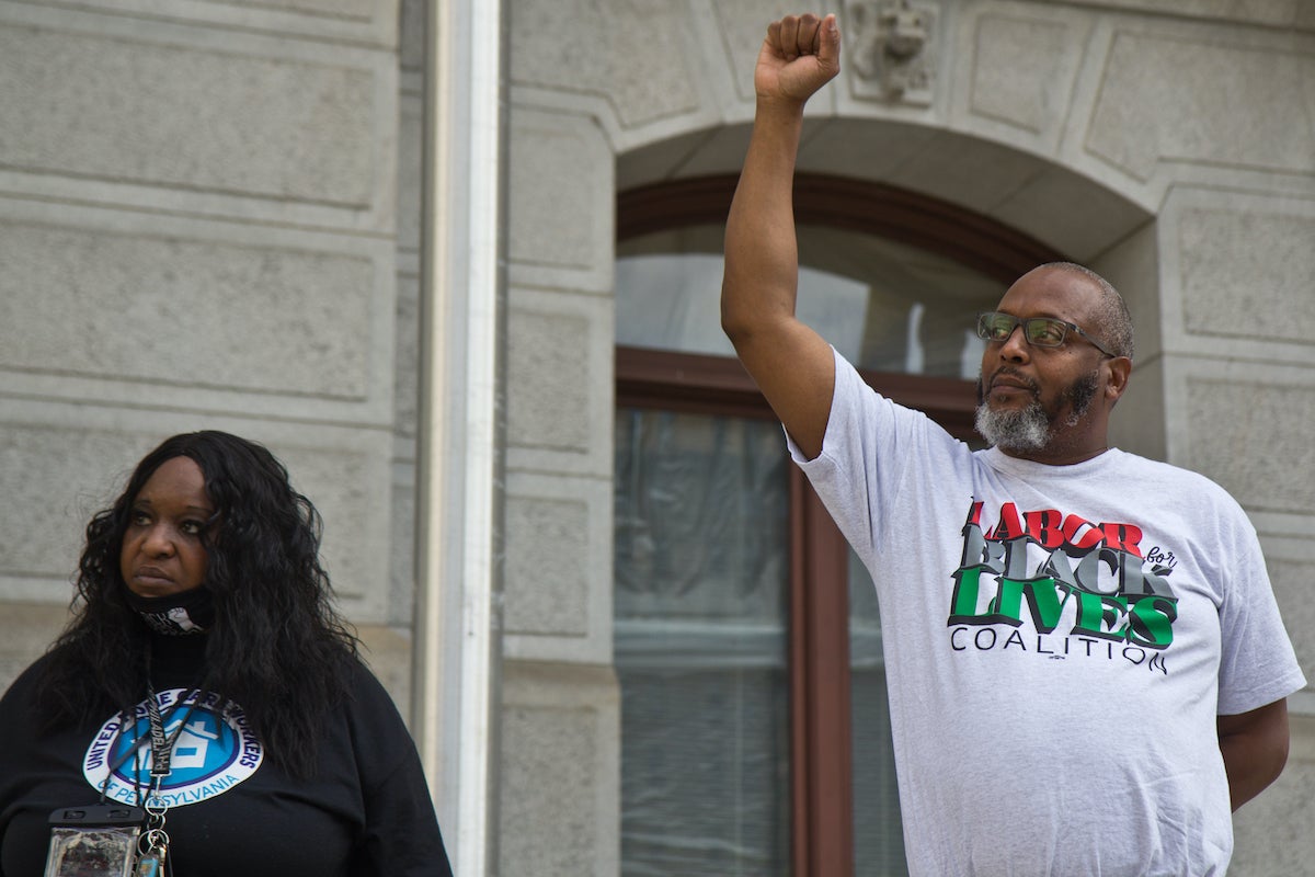 Wendell Royster, Vice President of Long Term Care with PA SEIU Healthcare and co-founder of the Labor for Black Lives Coalition (right), raises a fist in support of workers, next to home care worker with UWHP, Lolita Owens (left) at a vigil for George Floyd on the two-year anniversary of his murder outside City Hall in Philadelphia on May 25, 2022. (Kimberly Paynter/WHYY)