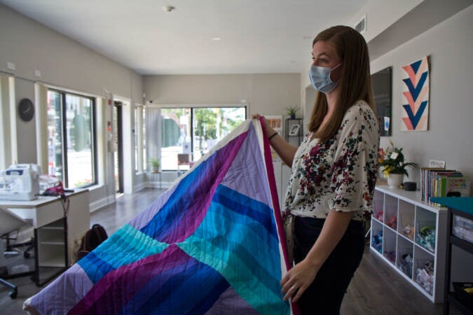 Melissa Clouser, owner of Cut & Sew, shows off student work at her store in Northwest Philadelphia. (Kimberly Paynter/WHYY)