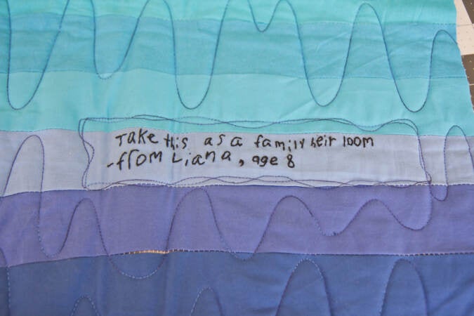 Melissa Clouser stitched quotes from students onto a quilt top made for a refugee family arriving to Philadelphia without any belongings. (Kimberly Paynter/WHYY)