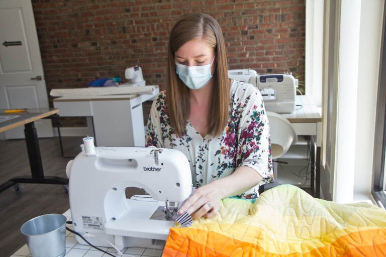 Melissa Clouser, owner of Cut & Sew, edges a quilt top she made with students to be donated to a refugee family. (Kimberly Paynter/WHYY)