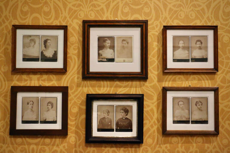 Framed photographs are hung on a wall with yellow wallpaper.