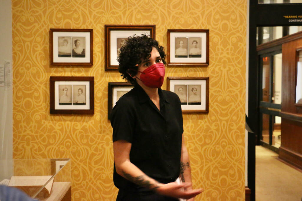 Assistant curator Sophia Dahab stands in front of a part of the "Hearing Voices" exhibition.