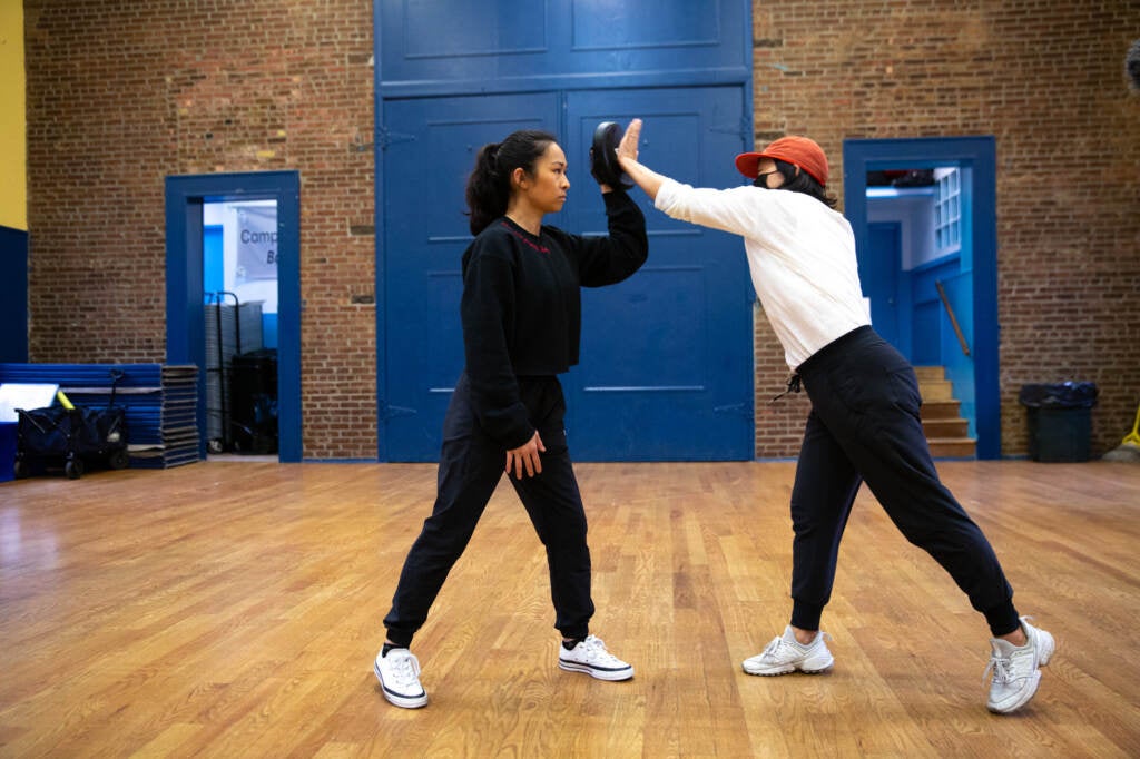 Jess Ng practices self-defense moves in a gym with another person.