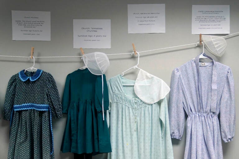 Dresses donated by sexual assault survivors from Amish and other plain-dressing religious groups hang on a clothesline beneath a description of each survivors' age and church affiliation, on Friday, April 29, 2022, in Leola, Pa. (AP Photo/Jessie Wardarski)