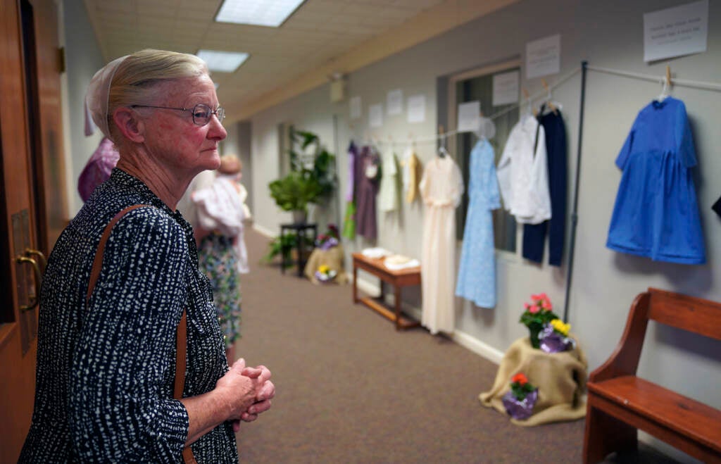 Sara Ann Petersheim looks at the clothes of sexual assault survivors from Amish, Mennonite and other plain-dressing religious groups on display at a child abuse prevention seminar, on Friday, April 29, 2022, in Leola, Pa. Similar exhibits held nationwide aim to shatter the myth that abuse is caused by a victim's clothing choice