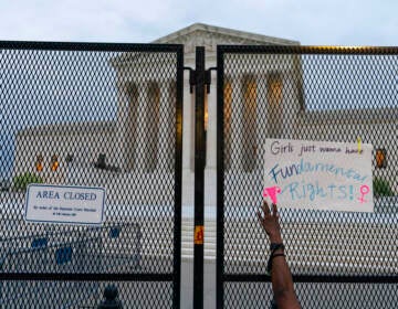 A demonstrator places a sign on the anti-scaling fence outside of the U.S. Supreme Court Thursday, May 5, 2022 in Washington. A draft opinion suggests the U.S. Supreme Court could be poised to overturn the landmark 1973 Roe v. Wade case that legalized abortion nationwide, according to a Politico report released Monday. (AP Photo/Alex Brandon)