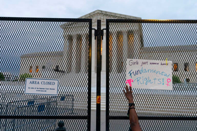 A demonstrator places a sign on the anti-scaling fence outside of the U.S. Supreme Court Thursday, May 5, 2022 in Washington. A draft opinion suggests the U.S. Supreme Court could be poised to overturn the landmark 1973 Roe v. Wade case that legalized abortion nationwide, according to a Politico report released Monday. (AP Photo/Alex Brandon)