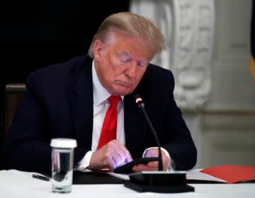 File photo: President Donald Trump looks at his phone during a roundtable with governors on the reopening of America's small businesses, in the State Dining Room of the White House in Washington, June 18, 2020. (AP Photo/Alex Brandon, File)