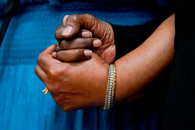 The daughters of Ruth Whitfield, a victim of shooting at a supermarket, Angela Crawley (left) and Robin Harris, hold hands during a news conference in Buffalo, N.Y., Monday, May 16, 2022. (AP Photo/Matt Rourke)