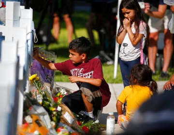 A child writes a message on a cross at a memorial site for the victims killed in this week's elementary school shooting in Uvalde, Texas, Thursday, May 26, 2022. (AP Photo/Dario Lopez-Mills)