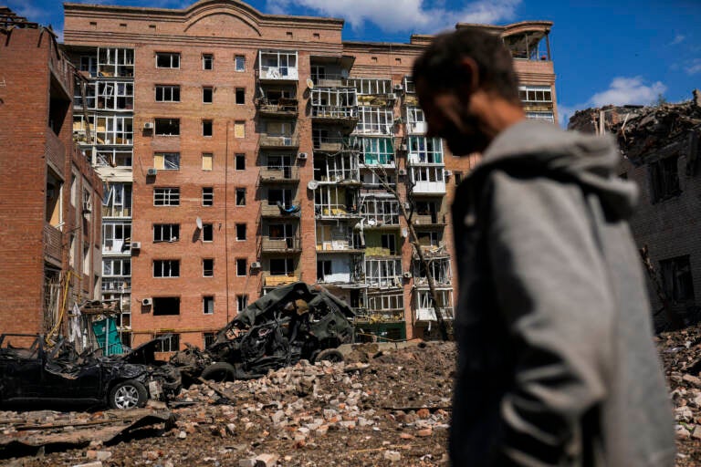 FILE - A man walks next to heavily damaged buildings and destroyed cars following Russian attacks in Bakhmut, Donetsk region, eastern Ukraine, Tuesday, May 24, 2022. The region, along with neighboring Luhansk, is part of the Donbas, where Russian forces have focused their offensive. (AP Photo/Francisco Seco, File)