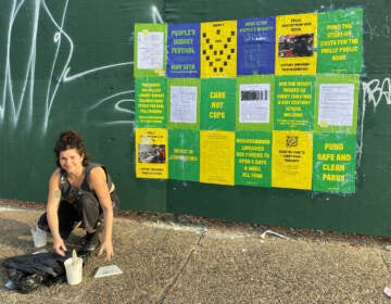 Artist Blanche Brown puts up posters for the People's Budget Festival.