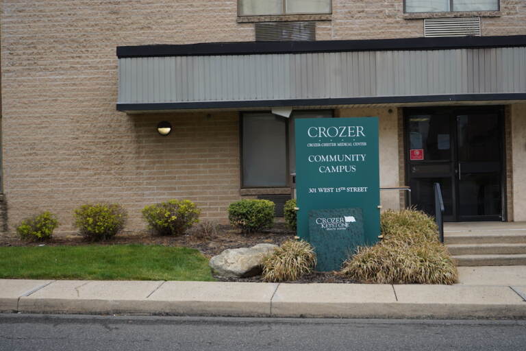 A sign and entrance are visible for a tan brick building.