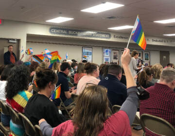 School board meeting attendees wave LGBTQ pride flags