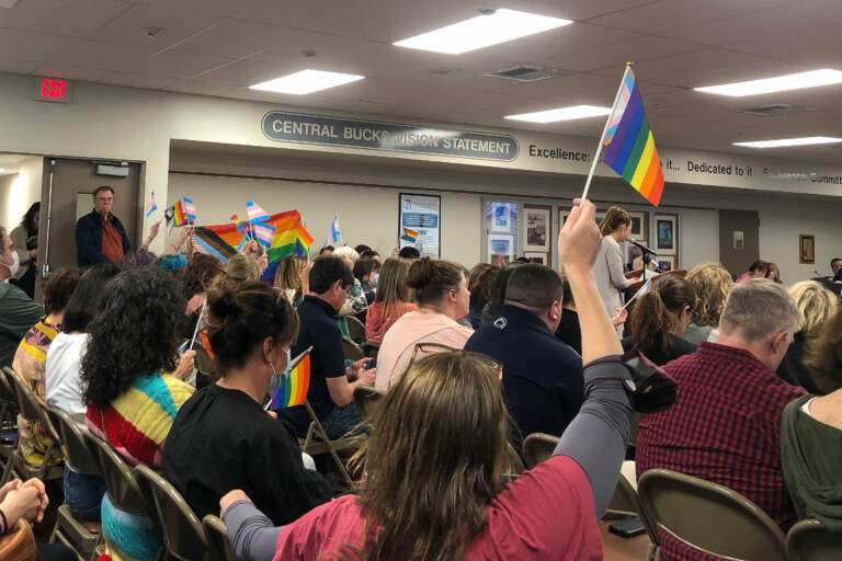 School board meeting attendees wave LGBTQ pride flags