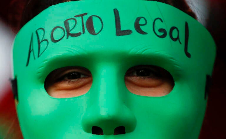 An abortion-rights activist wears a mask with text that reads in Spanish 