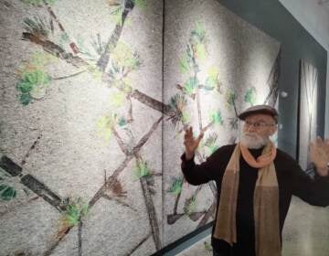 Puerto Rican artist Antonio Martorell stands in front of an artwork depicting a tree.